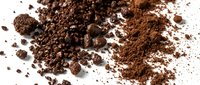 Ground cocoa powder and cocoa nibs scattered on white surface, showing texture and granules for baking, cooking, and culinary applications.