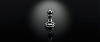 Silver metallic chess pawn piece standing alone on reflective black surface with dramatic spotlight lighting creating mirror reflection and shadows.