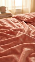 Cozy unmade bed with soft coral pink bedding and warm morning sunlight streaming through window creating peaceful bedroom atmosphere for rest and relaxation.