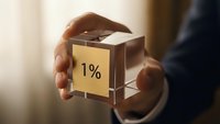 Businessman hands holding transparent glass cube with golden 1% label representing small percentage, minority share or exclusive premium offer concept.