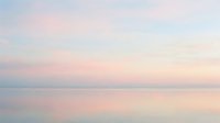 Serene dawn seascape with soft pastel pink and blue hues reflecting on calm ocean waters, conveying tranquility and peaceful morning atmosphere for wellness and meditation content.