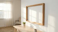 Wooden frame mockup on white wall in bright minimalist interior with natural light, table, and plant for art and print display.