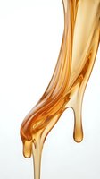 Golden amber liquid flowing and dripping against white background, isolated oil or honey stream for cosmetics, skincare, wellness and beauty product design applications.