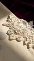Elegant ivory lace applique with intricate floral embroidery and pearl beading on silk fabric for bridal gown and wedding dress design projects.