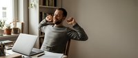 Happy father and daughter embracing at home office desk with laptop, showing family bonding during remote work. Parenting balance concept.