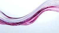 Elegant flowing pink and purple wave with sparkling particles creates dynamic motion against white background, suitable for luxury cosmetic advertising.