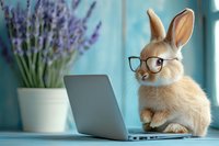 Funny bunny wearing glasses working on laptop computer with lavender flowers in background, concept of smart work and education for children's design.