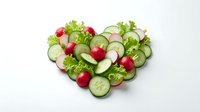 Fresh vegetables arranged in heart shape with radishes, cucumbers and lettuce on white background. Healthy eating and nutrition concept for food blogs and wellness content.