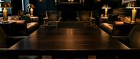 Elegant conference room with dark wood table, leather chairs, and warm ambient lighting for corporate meetings and business presentations.