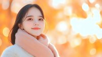 Young Asian woman with gentle smile against warm bokeh background wearing cozy pink sweater, expressing happiness and serenity in soft autumn lighting.