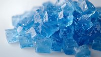 Bright blue translucent crystal cubes scattered on white surface with soft shadows and light reflections, creating fresh cool aesthetic for food and beverage designs.