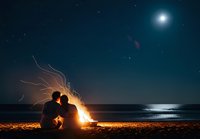 Romantic couple silhouette by campfire on beach under starry night sky with full moon reflecting on ocean waves for Valentine's Day concepts.