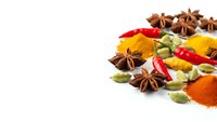Colorful spices and herbs scattered on white background including star anise, turmeric, cardamom, chili peppers creating aromatic cooking ingredients display.