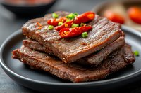 Grilled marinated tofu steaks with chili peppers and green onions on dark plate, plant-based protein meal for healthy vegetarian and vegan cooking recipes.