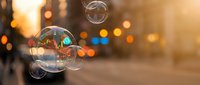 Soap bubbles floating in warm golden sunlight with blurred city lights creating magical bokeh effect in urban evening atmosphere.