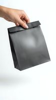Hand holding black paper shopping bag isolated on white background for retail packaging and branding mockup design.