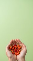 Hands holding fresh red chili peppers against soft green background. Isolated on pale backdrop, suitable for food, cooking, wellness, and culinary design projects.
