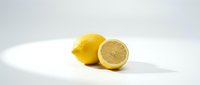 Fresh yellow lemons on clean white background, one whole and one cut in half showing juicy interior, perfect for healthy cooking and natural remedies.