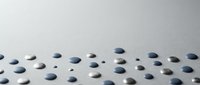 Scattered navy blue and white pills or tablets on clean white surface for medical pharmaceutical healthcare concept.