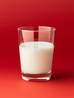 Glass of fresh white milk on vibrant red background for healthy breakfast beverage dairy product nutrition concept.