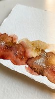 Abstract watercolor paint stroke in warm autumn colors with salt texture effects on white textured paper for artistic backgrounds and creative projects.