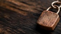 Rustic wooden pendant on dark textured background with shallow depth of field. Minimalist jewelry photography highlighting natural wood grain and craftsmanship.