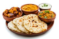 Traditional Indian food platter with naan bread, butter chicken curry, tandoori chicken wings and yogurt raita sauce served in clay bowls on wooden plate.
