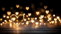 Romantic heart-shaped bokeh lights creating warm golden glow on wooden surface for Valentine's Day celebrations and love-themed designs.