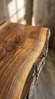 Raw wooden plank with natural bark edge and warm grain texture, illuminated by soft window light in rustic interior setting for design and decor projects.