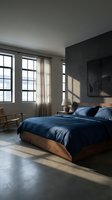 Modern minimalist bedroom with navy blue bedding, wooden bed frame, concrete floors and industrial windows creating serene sleeping space.