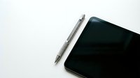 Modern silver pen and black tablet device on clean white background for business and technology applications.