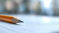 Sharp wooden pencil tip on lined paper with soft blurred background, macro photography highlighting writing instrument details for education and creativity concepts.