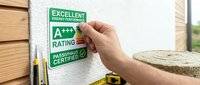 Hand placing energy efficiency rating label on wall showing A+++ excellent performance certification for sustainable building construction and green home improvement.