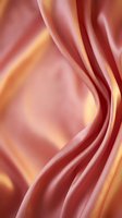 Luxurious coral pink silk fabric with golden highlights flowing in elegant waves creating smooth curves and soft shadows for premium textile design.