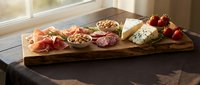 Gourmet charcuterie board with prosciutto, salami, artisan cheeses, nuts and cherry tomatoes on rustic wooden platter for entertaining and appetizers.