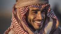 Middle Eastern man with traditional keffiyeh headscarf smiling warmly in golden sunlight, showcasing cultural heritage and authentic expression.