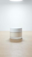 Minimalist cosmetic jar with cream on wooden surface against neutral background for skincare and beauty product mockup presentations.