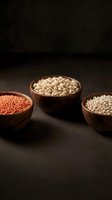 Wooden bowls filled with red lentils, white beans, and pearl barley arranged on dark surface for cooking and nutrition concepts.