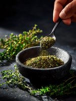 Fresh thyme herbs in stone mortar with spoon and scattered sprigs on dark background, dramatic lighting highlights aromatic spices for cooking.