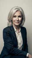 Confident mature Caucasian businesswoman with silver hair in dark suit jacket smiling warmly at camera in professional corporate portrait setting.