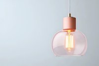 Modern pendant lamp with pink glass shade and glowing vintage Edison bulb against minimal gray wall, creating warm atmospheric lighting.