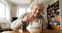 Happy senior Caucasian woman putting coins into pension savings jar at home, retirement financial planning and security concept for elderly people.