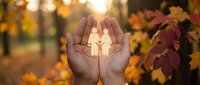 Hands holding glowing family silhouette in autumn forest setting. Concept for family protection, care, insurance, and togetherness during fall season.