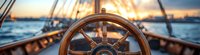 Wooden ship wheel on sailing yacht against dramatic sunset sky and ocean waves, maritime navigation equipment in warm golden light panoramic view.