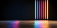 Vertical neon light tubes in rainbow colors glowing on black wall with wooden floor, colorful reflections creating modern minimalist atmosphere.