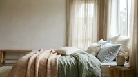 Cozy bedroom with unmade bed, soft linen bedding, decorative pillows, and natural light from window with sheer curtains for home decor and interior design inspiration.