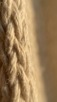 Twisted natural fiber rope with warm golden lighting creating texture and depth, suitable for crafts, construction, maritime, and industrial design projects.