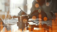 Financial market data and stacked coins on desk with stock chart overlay and warm bokeh lighting effect, business analysis concept for investment trading.