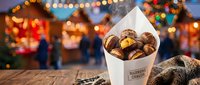Steaming roasted chestnuts in a paper cone at a festive Christmas market, warm bokeh lights glowing in the background, cozy winter street food scene.
