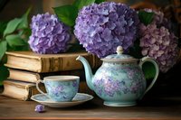 Vintage teapot and cup with purple floral pattern alongside fresh hydrangea blooms and antique books on wooden surface in moody natural lighting.